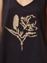 Musculosa de algodón color azul marino, con escote en V y un bordado artesanal de flor en el frente con contorno naranja y relleno dorado.