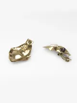 Pendientes metálicos con diseño en relieve de forma orgánica, decorados con una perla natural y una cuenta oscura. Poseen cierre de broche.