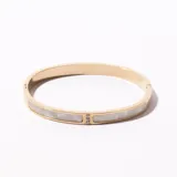 Brazalete rígido dorado con incrustaciones de nácar y pequeños brillantes.