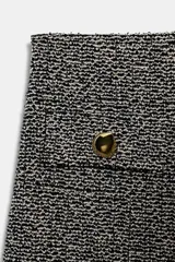 Pantalón de tiro medio, pierna ancha, confeccionado en tejido texturado de color claro con hilo metalizado. Presenta falsos bolsillos delanteros con botones metálicos dorados.