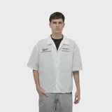 Camisa de manga corta color blanco, con corte oversize y cuello tipo polo. Presenta un estampado gráfico en la espalda con el logo y nombre de la marca Venefo Industries.
