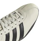 Championes Adidas modelo Tokyo, de diseño clásico y perfil bajo, confeccionados en cuero color blanco hueso con las icónicas tres tiras laterales y detalles en el talón en color negro. Presenta suela de goma negra y cordones al tono.