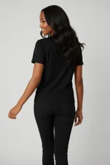 Remera de algodón color beige con estampado floral en tonos azules en el centro del pecho y detalle de texto manuscrito.