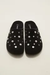 Suecos tipo zueco color negro con acabado de gamuza, decorados con tachas metálicas plateadas circulares. Poseen suela plana y diseño abierto en el talón.