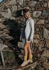 Campera de cuero color beige claro, estilo sobrecamisa o chaqueta ligera, con cuello camisero, cierre frontal con broches de nácar y dos bolsillos de parche en el pecho.