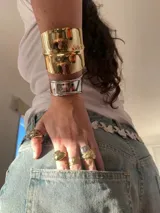 Brazalete rígido de diseño ancho y superficie lisa con acabado brillante en tono dorado.