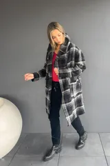 Abrigo de corte trench con estampado de tartán en tonos negro y gris. Presenta solapas amplias, bolsillos frontales y diseño abierto.