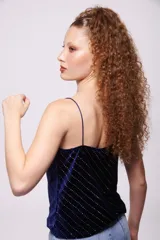 Top negro de terciopelo con breteles finos y escote en V. Presenta líneas verticales de lentejuelas plateadas.