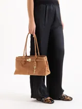 Cartera tipo shopper de cuero vacuno marrón, con silueta estructurada, doble asa de hombro y herrajes metálicos plateados. Incluye tira decorativa con candado y llave colgantes.
