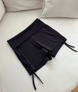 Short negro de calza con cintura alta y cordones ajustables laterales.