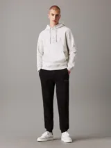 Pantalón de chándal negro de felpa de mezcla de algodón reciclado, con cintura elástica con cordón, puños de canalé, bolsillos con ranura y bolsillo trasero. Presenta un monograma bordado de Calvin Klein en la pierna.