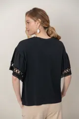 Remera de algodón color blanco, con cuello redondo y mangas cortas holgadas que presentan detalles de encaje broderie.