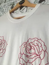 Remera blanca de algodón con dos rosas rojas bordadas en el frente.