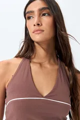 Top halter negro con escote en V y detalle de vivo blanco horizontal. Presenta un diseño ajustado al cuerpo y espalda descubierta con tiras regulables.