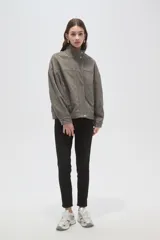 Campera de corte holgado en color gris, con cuello alto, cierre frontal oculto y mangas largas. Presenta costuras decorativas en el frente y bolsillos laterales.