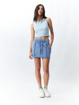 Minifalda color beige con elástico en la cintura, cordones ajustables y costuras marcadas en los laterales.