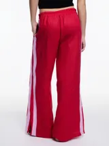 Pantalón de lino negro de calce relajado y tiro medio, con cintura elástica y cordón ajustable. Presenta tiras laterales en color gris claro que pueden anudarse en la parte inferior.