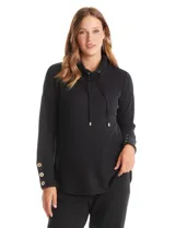 Buzo de tejido suave color gris melange, con cuello volcado ajustable mediante cordones con punteras metálicas. Presenta mangas largas con puños anchos decorados con botones metálicos, hombros caídos y un diseño de silueta holgada con ruedo redondeado y aberturas laterales.