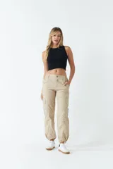 Pantalón cargo color beige de tiro medio, con bolsillos laterales tipo cargo y puños ajustables en los tobillos.