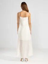 Vestido largo de color celeste confeccionado en tejido arrugado liviano. Presenta un diseño con escote recto, breteles finos y detalles de lazos en los laterales. Incluye bolsillos laterales, forro interno corto y un ruedo asimétrico con caída posterior más larga.