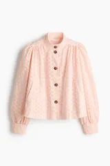 Blusa corta de algodón con diseño broderie de color rosado claro, cuello alto, mangas abullonadas con puños ajustados y cierre frontal de botones con efecto carey.