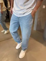 Jean de corte baggy en color azul claro, con diseño de cinco bolsillos y cierre frontal con botón y cremallera.