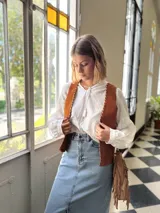 Cartera bandolera de cuero color camel, con forro interno de tela y flecos laterales.