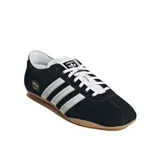 Championes Adidas modelo Tokyo, color negro con las tres rayas distintivas de la marca en blanco y detalles plateados en el talón y la lengüeta. Suela de goma color caramelo.
