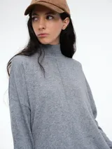 Sweater de tejido de punto color marrón, con cuello alto, corte amplio y tajos laterales en el ruedo. Presenta una costura vertical central en el frente y mangas largas con puños acanalados.