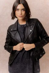 Chaqueta tipo biker de cuero sintético color marrón, con cierre frontal asimétrico, cuello con solapas y broches metálicos, y bolsillos laterales con cierre.
