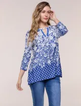 Blusa azul y blanca con estampado floral y geométrico, de calce suelto, con escote redondo, abertura tipo keyhole en el pecho, mangas tres cuartos y ruedo amplio con silueta evasé.
