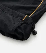 Pantalón deportivo de microfibra color negro, con corte holgado y diseño de piping contrastante en color amarillo. Cuenta con cintura elástica con cordón de ajuste, bolsillos laterales y logo bordado.