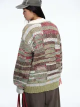 Cardigan de tejido de punto con diseño a rayas horizontales en tonos verdes, rojos y beige. Presenta cuello en V, cierre frontal con botones y dos bolsillos delanteros con solapa. Posee puños y ruedo acanalados en color verde claro.