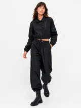 Pantalon estilo parachute verde militar con cintura elastizada ajustable mediante cordón, bolsillos laterales y puños ajustables en los tobillos.