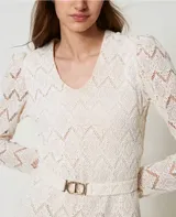 Vestido corto color blanco de encaje macramé con diseño geométrico, escote de pico, mangas largas abullonadas tipo guante con cremallera invisible en el bajo, cierre de cremallera en el lateral, bajo festoneado, forro de muselina de algodón y cinturón extraíble a juego con elástico y hebilla con el logotipo Oval T dorado, de corte recto.