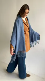 Ruana de tejido suave en color azul, con diseño de flecos en los extremos. Presenta una textura cálida y versátil para complementar diversos atuendos.