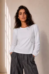 Remera manga larga blanca con detalles de encaje vertical en el frente y puños elásticos.