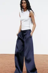 Top blanco de manga sisa con cuello redondo y corte ajustado al cuerpo.