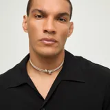 Collar de dos vueltas compuesto por pequeñas cuentas metálicas bañadas en plata y un dije central con forma de dos gotas.