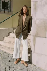 Blazer de lino color verde militar, con cuello solapa, hombreras y manga larga con puño revuelto con detalle a rayas. Cuenta con cierre frontal de un botón y bolsillos delanteros con solapa.
