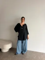 Blusa de viscosa con estampado de lunares, corte holgado, mangas tres cuartos y escote en V con botón central.