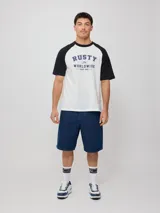 Remera blanca con mangas raglán negras y estampado frontal con el logo de Rusty en azul.