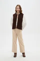 Chaleco de punto texturizado en color marrón chocolate, con cuello redondo y cierre frontal de botones a tono.