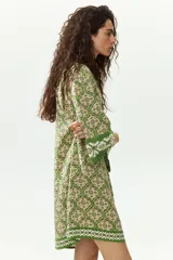 Vestido túnica corto de viscosa con estampado geométrico en tonos verdes y crudo, escote en V pronunciado tanto en el frente como en la espalda, mangas tres cuartos y diseño oversized.
