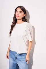 Remera de algodón peinado color negro, con mangas cortas de broderie con diseño calado y terminación festoneada. Presenta un corte oversize y cuello redondo.