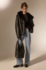 Bolso tipo hobo grande, de color negro, con diseño trenzado en la mitad inferior y asa de hombro integrada.