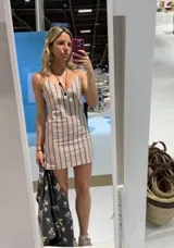 Vestido corto a rayas verticales, confeccionado en lino y algodón, con escote en V, cierre lateral y tajo en el ruedo.