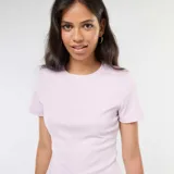 Camiseta rosa de punto de canalé fino con cuello redondo y corte ajustado. Presenta una abertura en el bajo. 