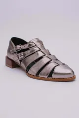 Sandalias bajas de cuero color dorado con tiras entrecruzadas y hebillas ajustables. Taco de madera.