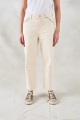 Pantalón jean color crudo, de tiro medio y corte recto, con bolsillos delanteros con bordado de motivos geométricos en tonos celeste y naranja.